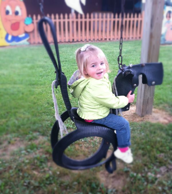 Raya on swing shaped like a pony and made of tires